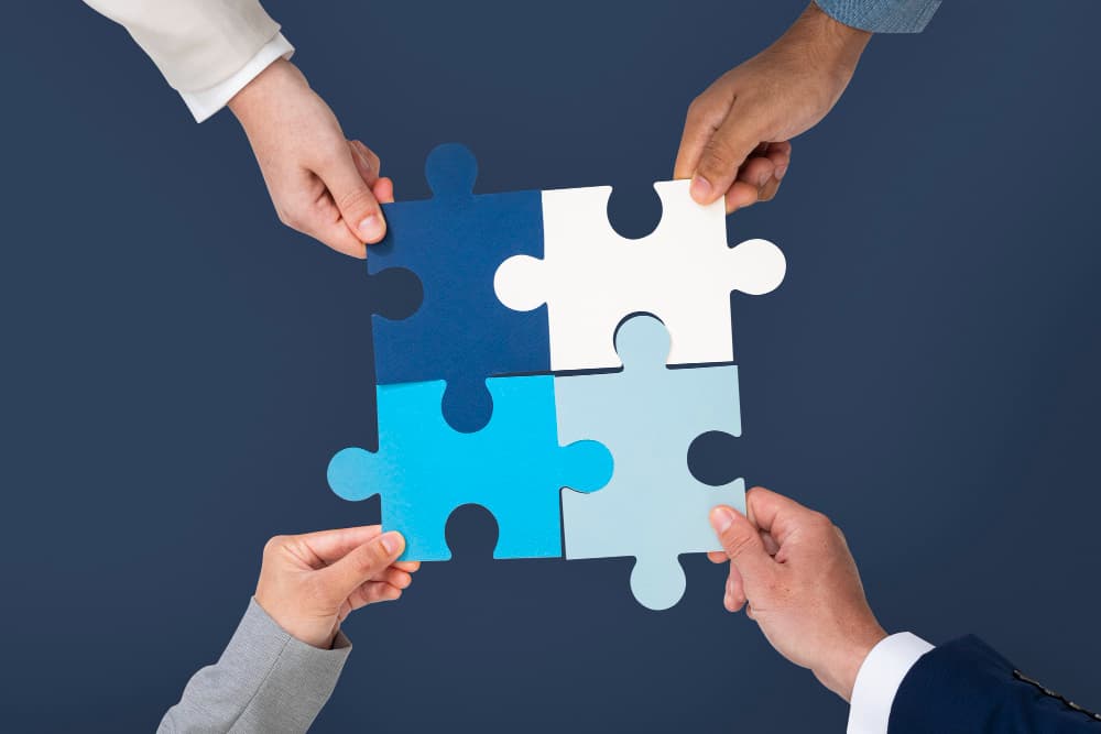 Four hands joinng pieces of puzzle
